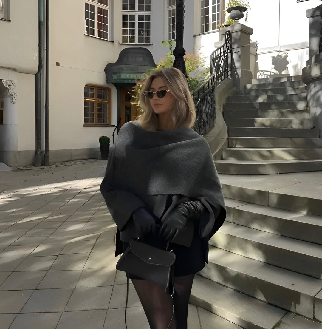 Elegant ytterplagg: draperad cape kappa med stilren design för en sofistikerad look.