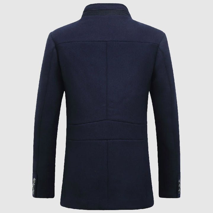 Man bär en elegant herrkappa med ståkrage och rutigt foder. Stilrent ytterplagg för herrmode under höst/vinter.