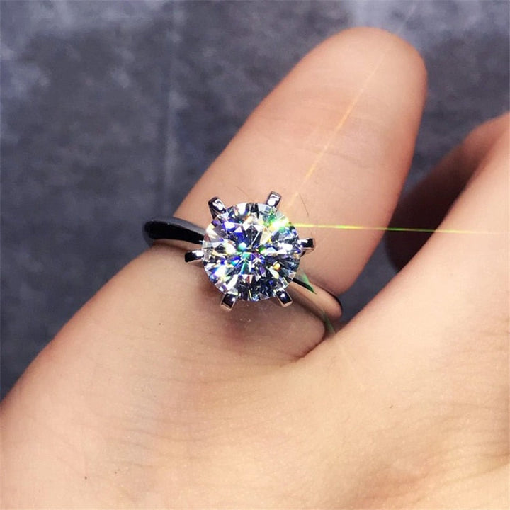 Närbild på elegant löftesring för dam, vitguldpläterad med central diamantstil zirkonia & mindre sidostenar.
