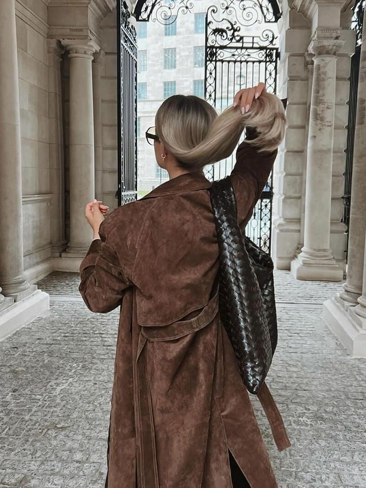 Närbild av elegant kvinnors lång trenchcoat med fina detaljer, stilren och klassisk höstkappa.