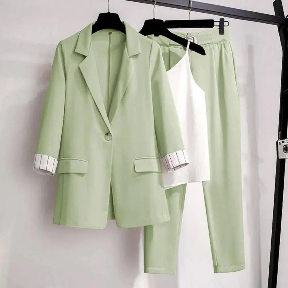 Detaljbild av ett kvinnors eleganta kavajset i modern kontorsstil. Innehåller kavaj, byxor och topp.