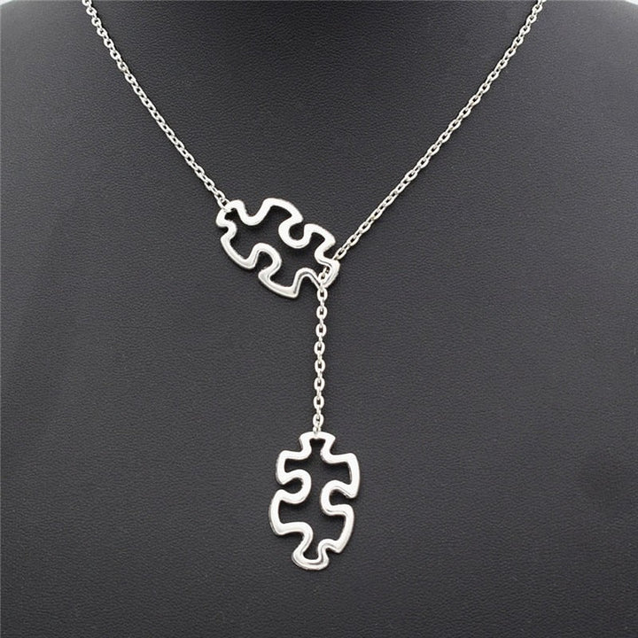 Symboliskt damhalsband med pusselberlock som stödjer autismmedvetenhet. Meningsfull gåva.
