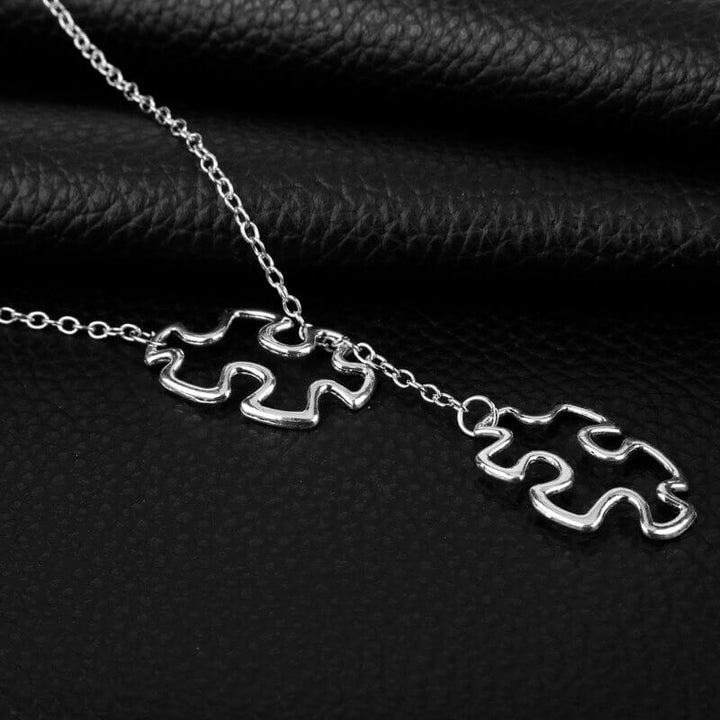 Närbild av pusselberlock på halsbandet. Damhalsband i rostfritt stål för autismmedvetenhet.