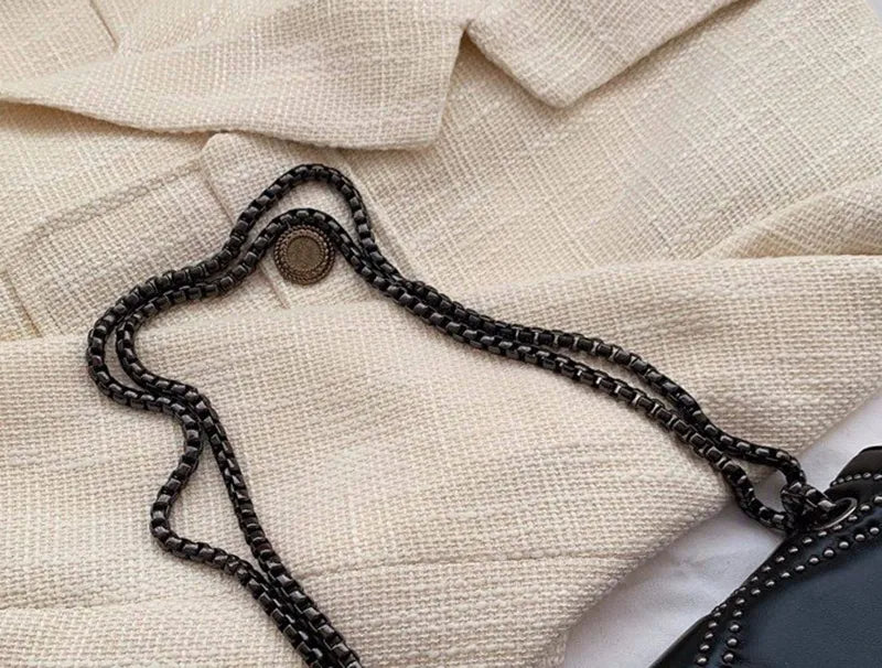 Modeaccessoar: svart dam axelremsväska med nitar och elegant metallkedja, året runt.