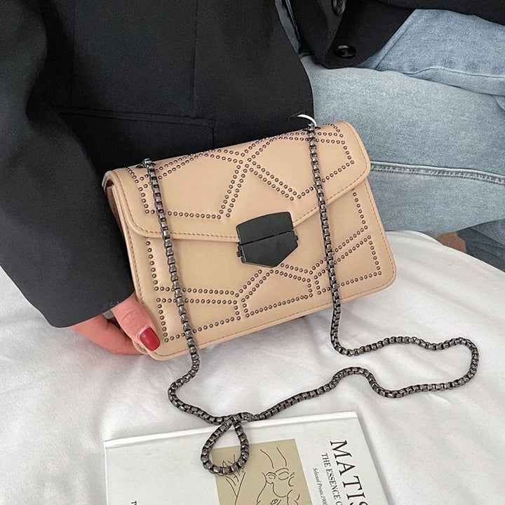 Glamourös svart dam crossbody med nitar och en chic metallkedja, perfekt för fest.