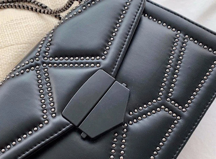 Svart crossbody väska för kvinnor med nitar och en snygg kedjerem, praktisk och chic.