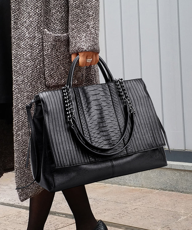 Exklusiv svart elegant damhandväska i patchworkstil med glänsande kedja. Trendig modeaccessoar.
