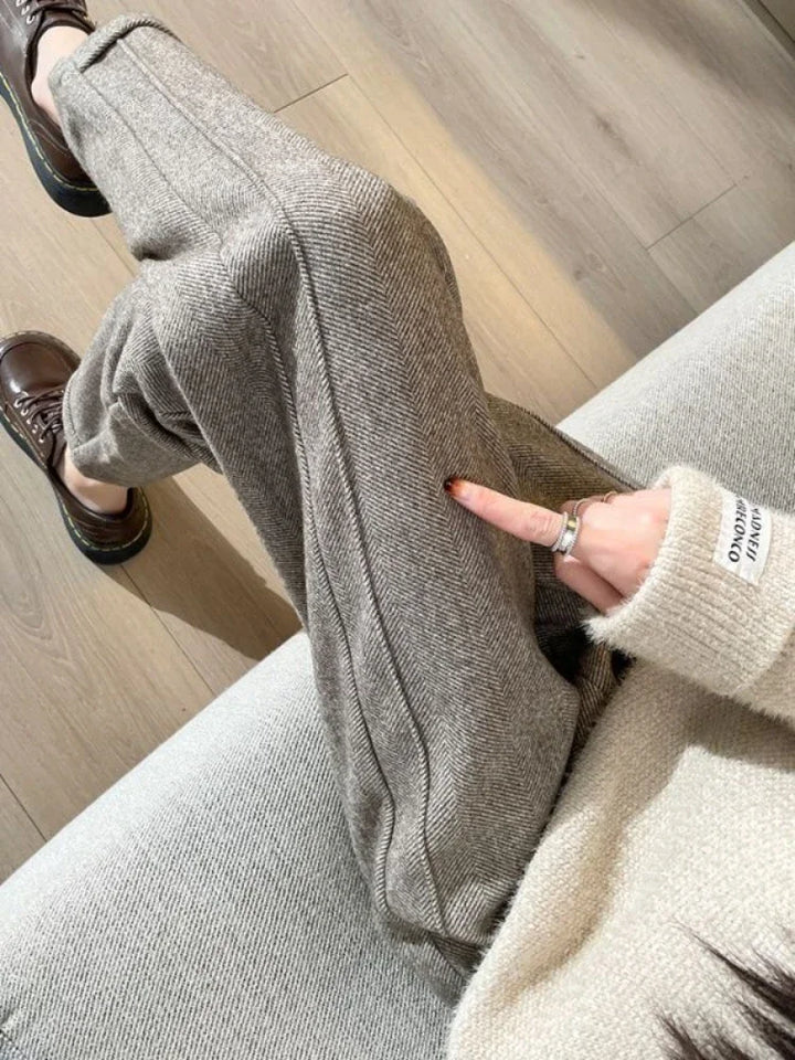 Helsotsbild av dam i eleganta svarta vida byxor i polyester, från sidan.