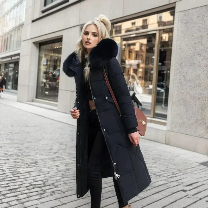 Kvinna poserar i elegant svart vinterkappa med fuskpäls. Perfekt damkappa för vintermode och värme.