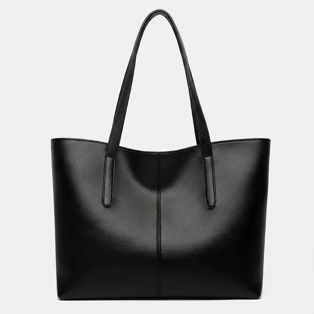 Dam bär elegant Jessy toteväska över axeln, perfekt för en stilren look på jobbet eller till vardags.