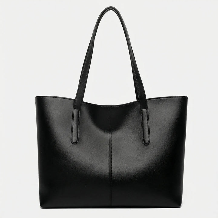 Dam bär elegant Jessy toteväska över axeln, perfekt för en stilren look på jobbet eller till vardags.