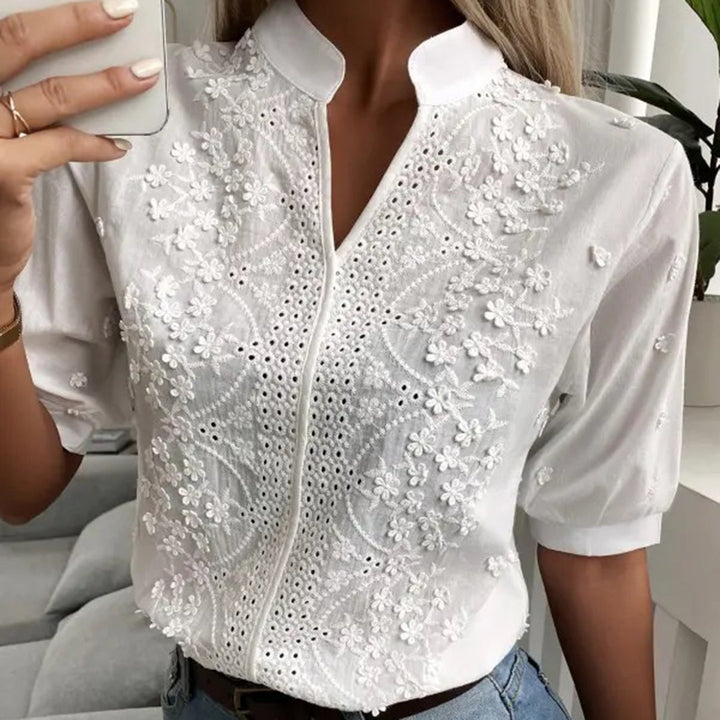 Snygg vit vardagsblus med spets och korta ärmar, ger en stilren och bekväm look för kvinnor.