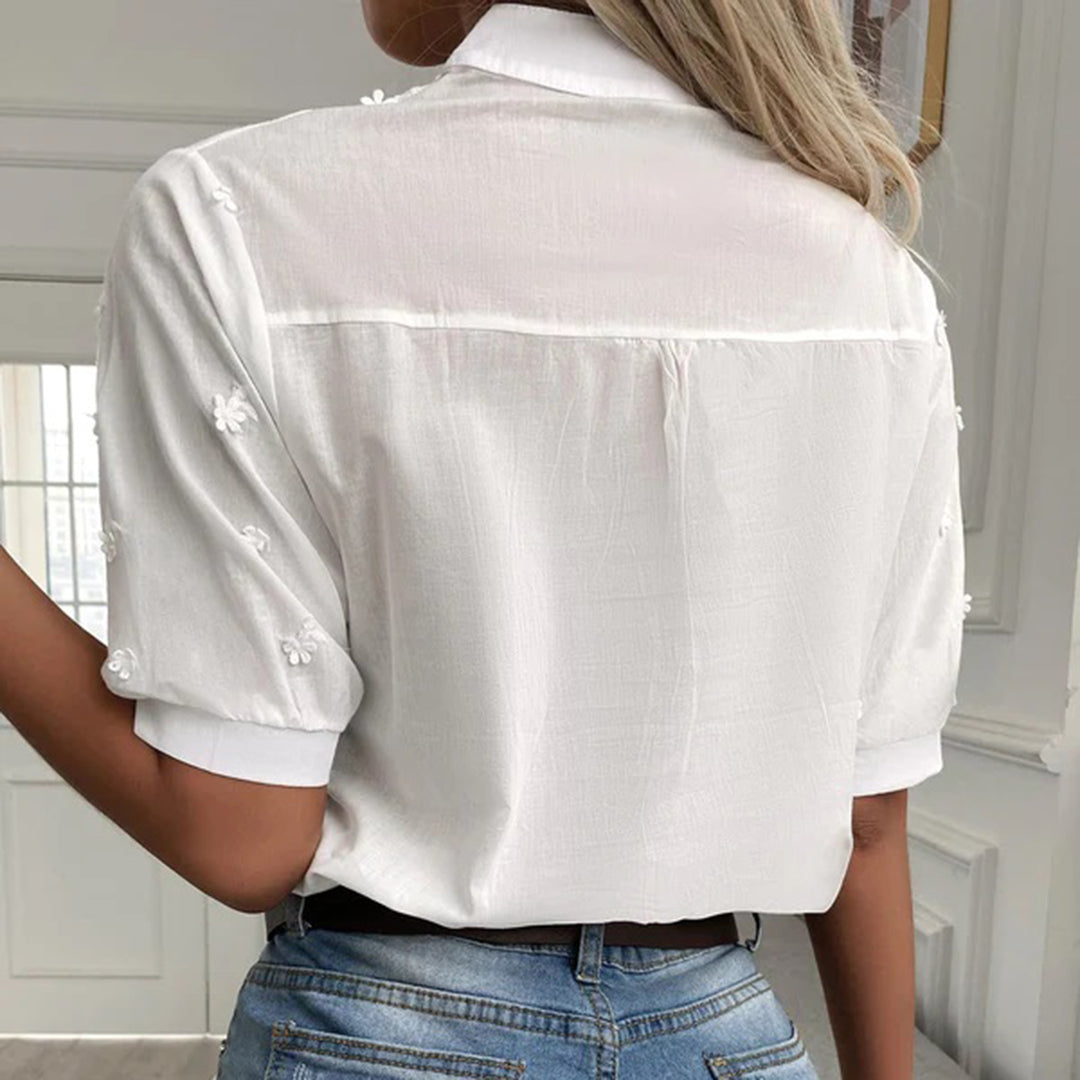 Vit vårblus med korta ärmar och spetsdetaljer, en mångsidig och elegant damblus.