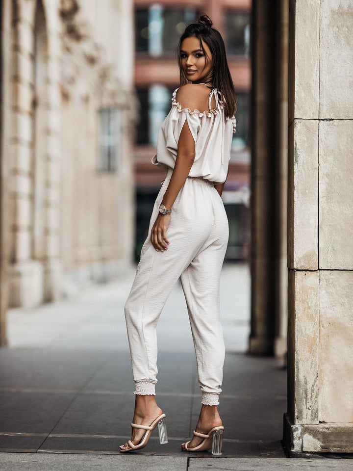 Trendig vit byxdress för dam, med V-ringning och off-shoulder design. Idealisk för fest & vardag.