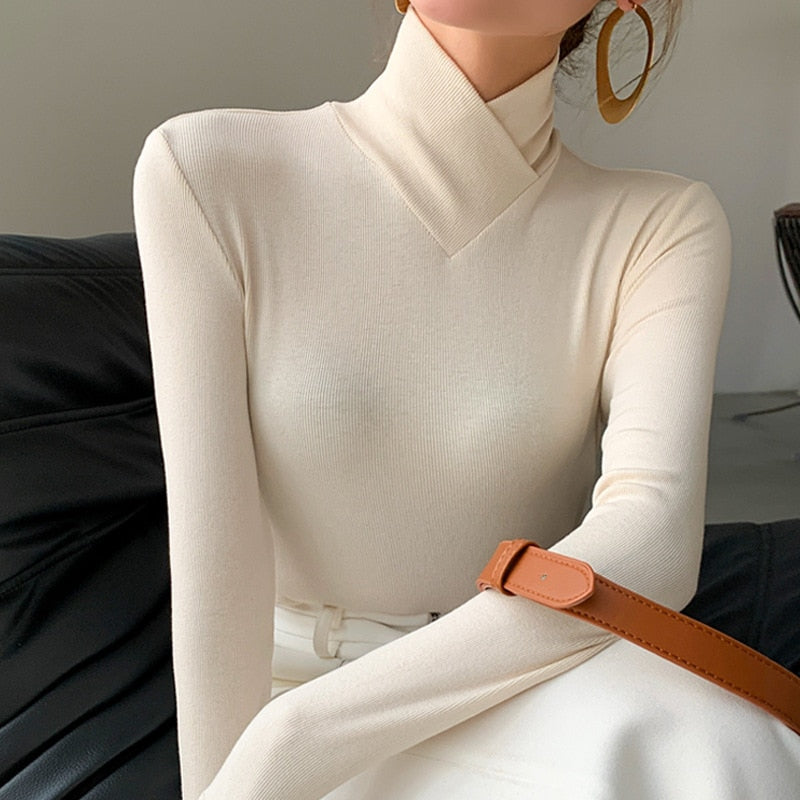 Elegant vit damtopp med mockhals, perfekt för vårmode och en stilren vardagslook. Figurnära passform med lång ärm.