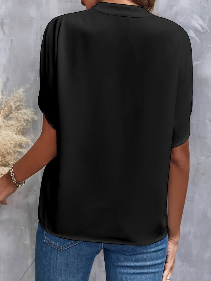 Modell bär en elegant kortärmad viskosblus, visar passformen och den flödande designen.