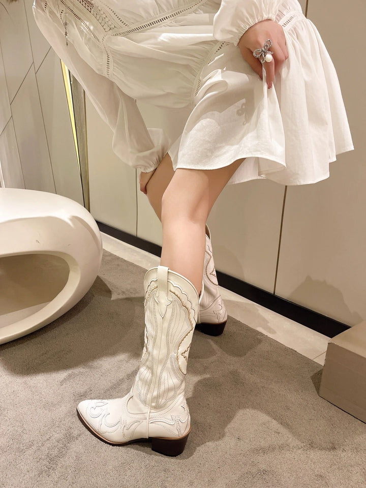 Ett par broderade mellanhöga damstövlar. Elegant western-stil med spetsig tå och fyrkantig klack för chic komfort.