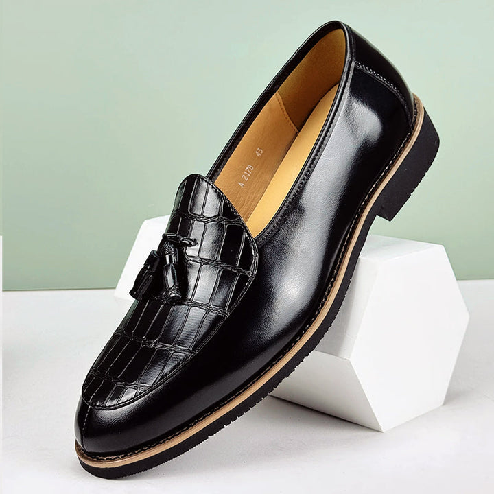 Stilrena svarta herrloafers med krokodilpräglad yta och dekorativa tofsar för en smart casual look.