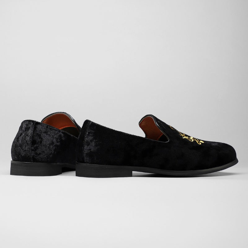 Detaljerad bild av mäns loafers med gyllene ornament, slip-on design och röd innersula. Formella herrskor.