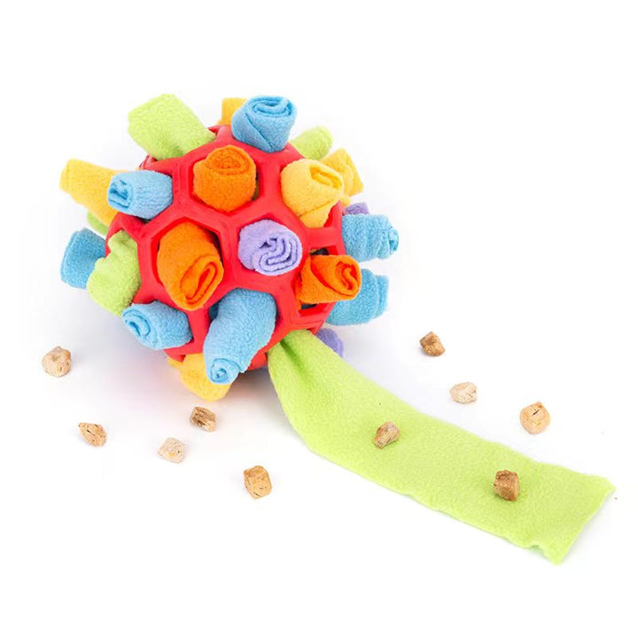 Glad hund leker med färgglad snusboll i fleece. Utmärkt för aktivering & berikning av valpar.