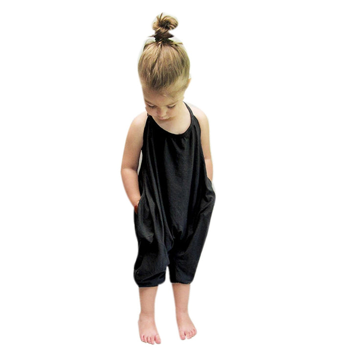 Flickmodell i färggrann halterneck-jumpsuit poserar glatt utomhus, visar lekfull stil.