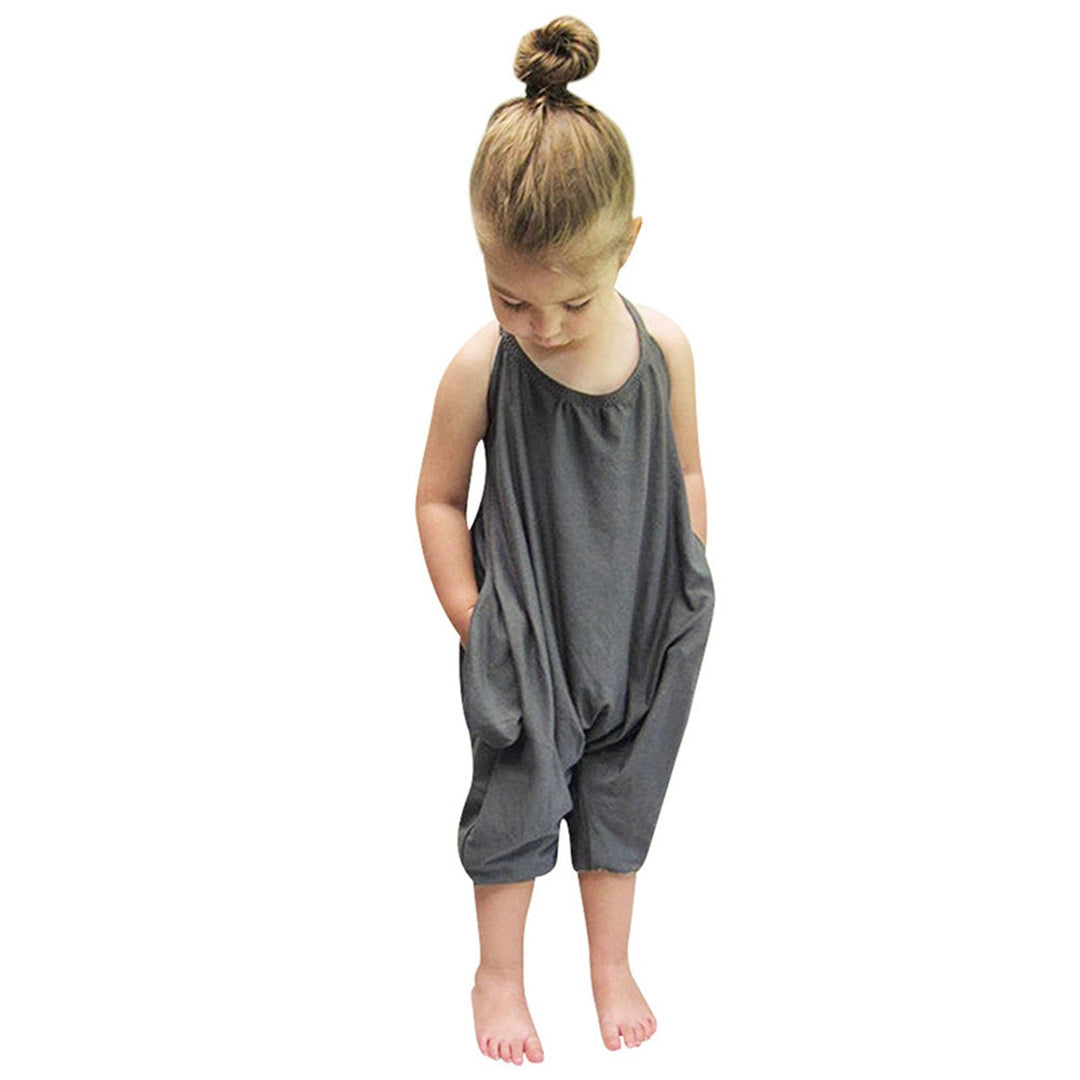 Barn i blåblommig halterneck-jumpsuit leker på gräsmattan, perfekt sommaroutfit för tjejer.