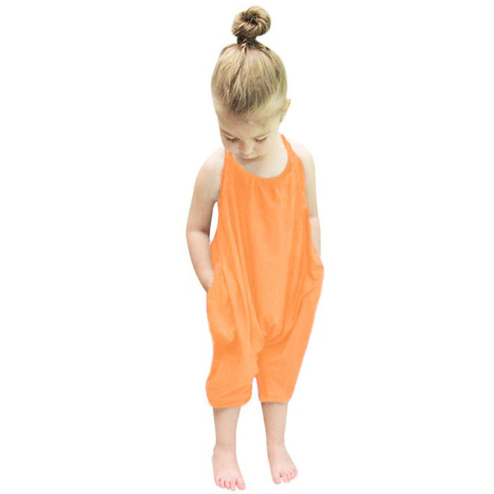 Glad flicka i trendig halterneck-jumpsuit och sandaler, redo för sommardagar, barnmode.