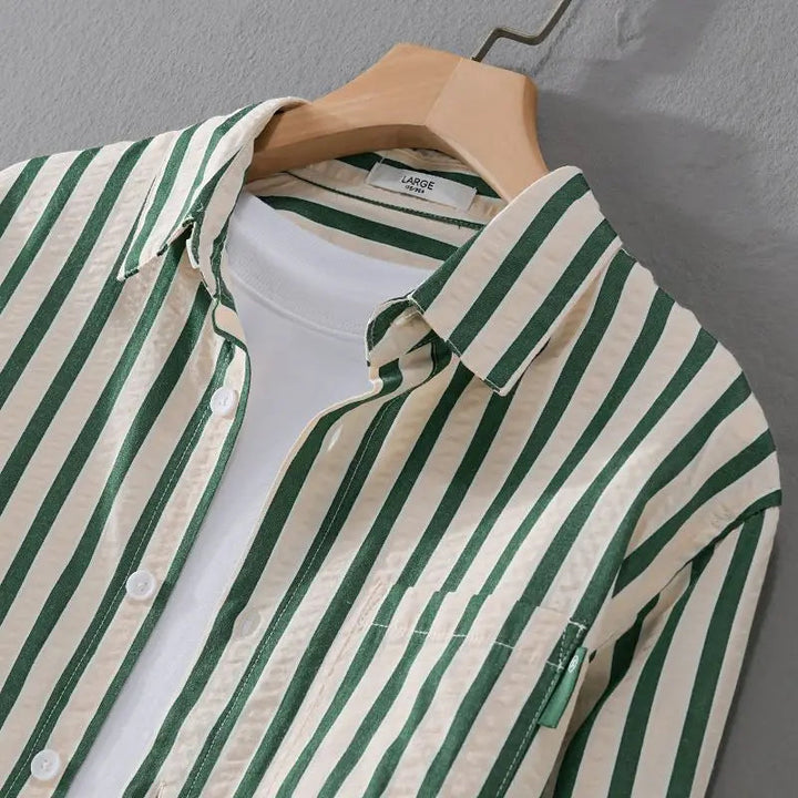 Detaljbild av en randig herrskjorta som framhäver det mjuka tyget och knapparna.