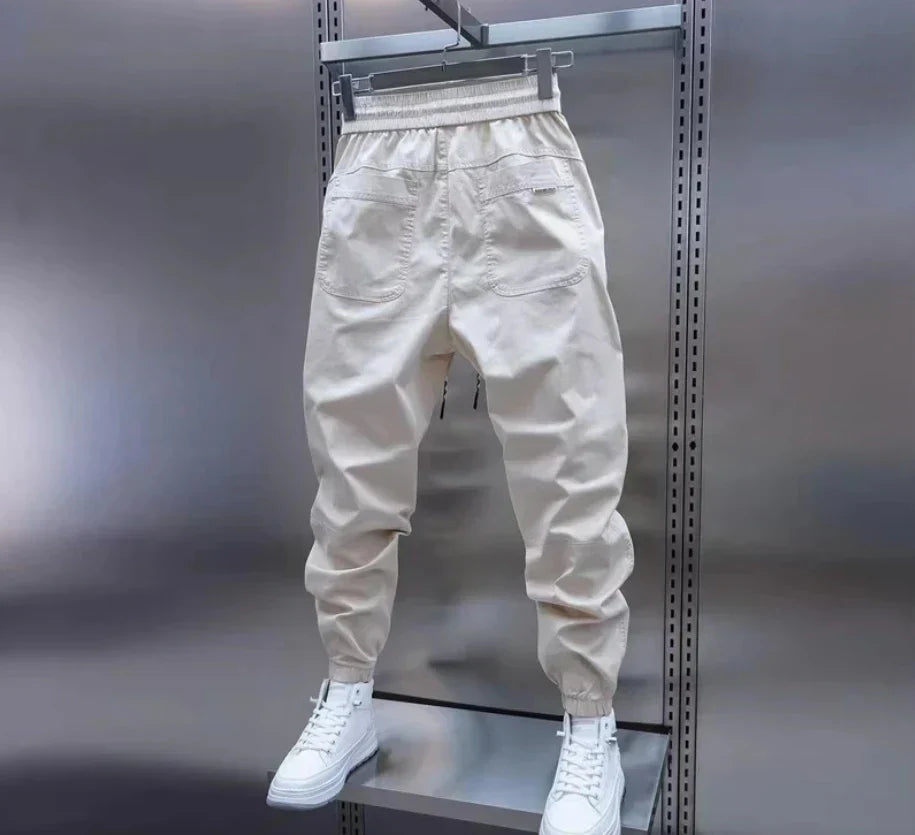 Vita träningsbyxor för herr, designade för aktivitet. Elastiska fritidsbyxor med stilren look.