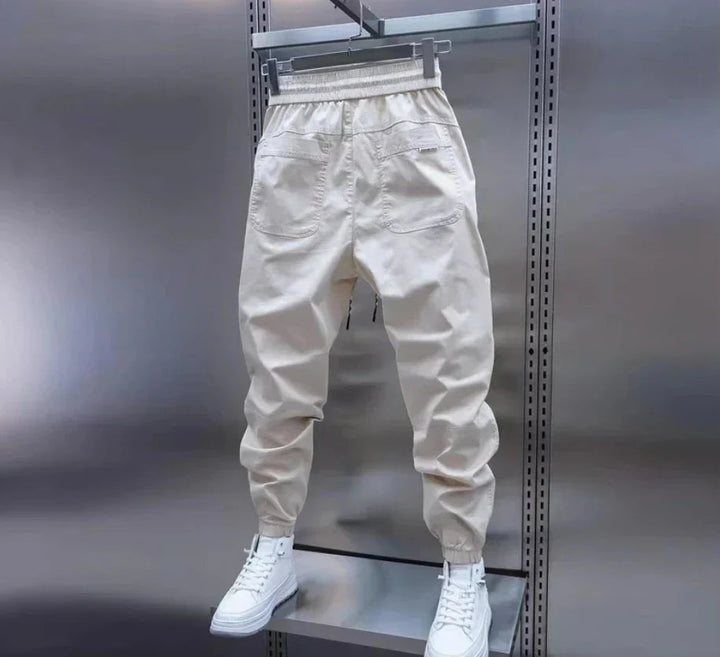 Vita träningsbyxor för herr, designade för aktivitet. Elastiska fritidsbyxor med stilren look.