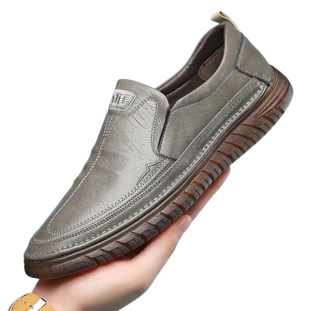 Närbild på textur av grå herr PU-läder loafers, visar detaljer av handgjort hantverk och söm.