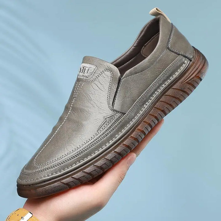 Herr loafers i PU-läder, svart och brun, sida vid sida, visar färgalternativen för denna bekväma sko.