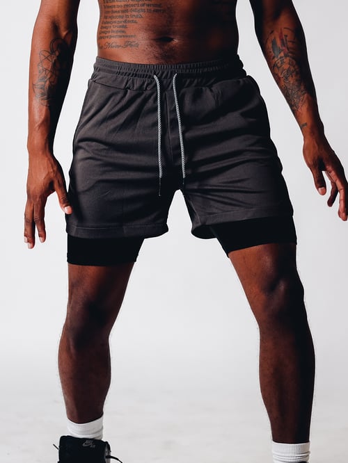 Närbild på de fuktdränerande och flexibla herrar 2-i-1 sportshortsen, idealiska för intensiv träning.