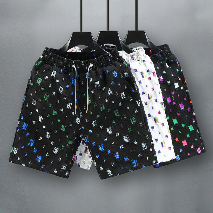 Närbild på herrarnas slitna jeansshorts med färgstarka detaljer, perfekt för en modern sommarlook.