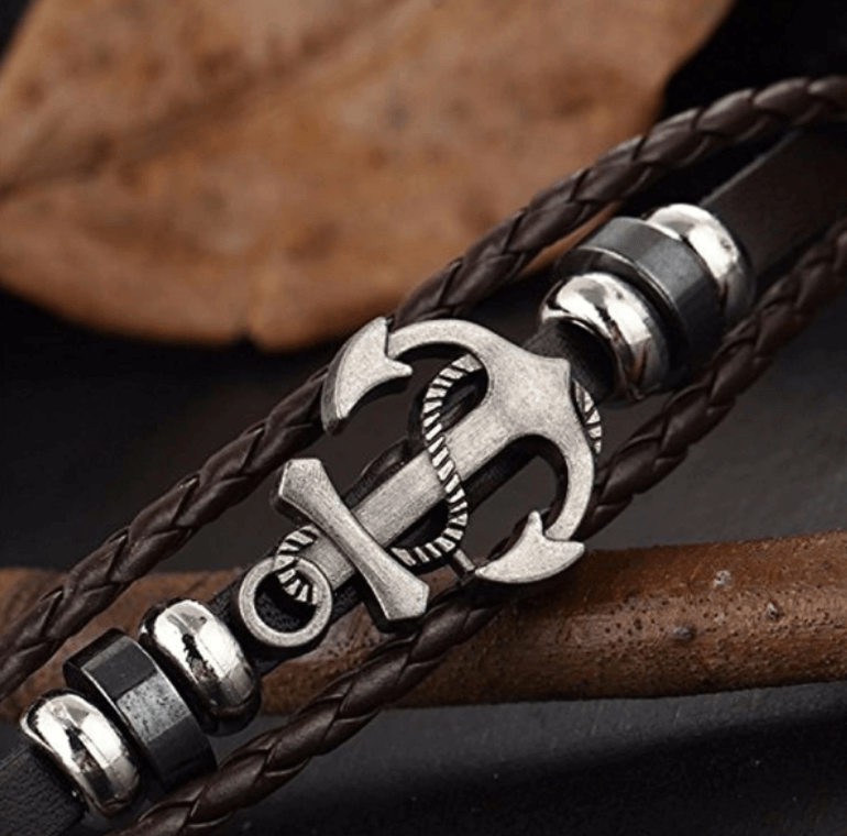 Man bär brunt läderarmband med silverfärgat ankare, snyggt på handleden. Klassiskt marint herr-smycke.