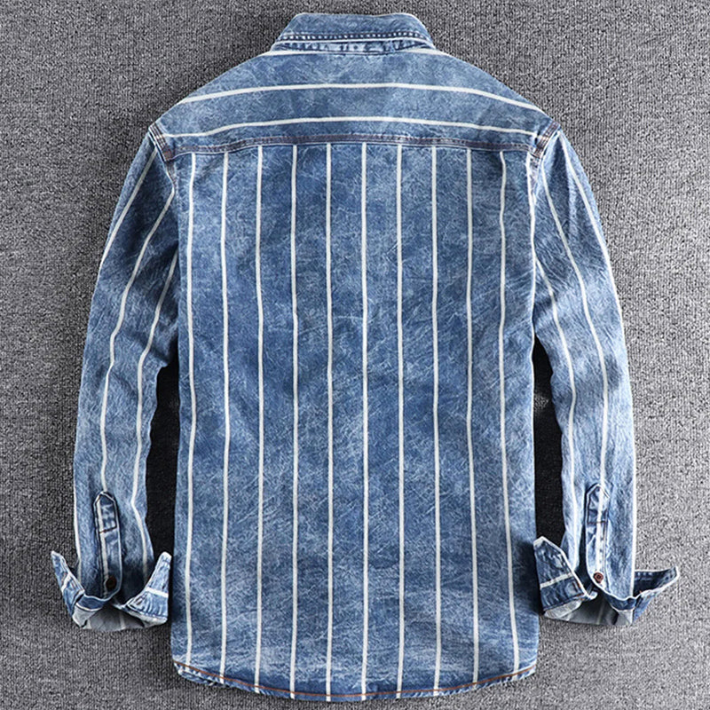 Man bär en snygg randig jeansskjorta som framhäver den avslappnade moderna designen.