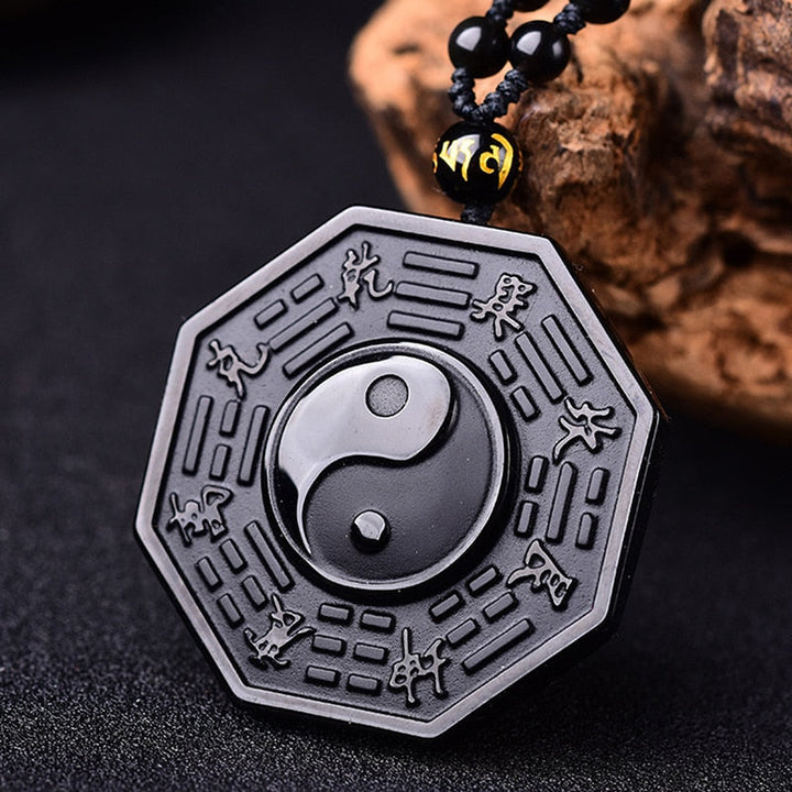 Detaljbild av polerad obsidian Yin Yang-berlock på herrhalsband, symboliserar harmoni.