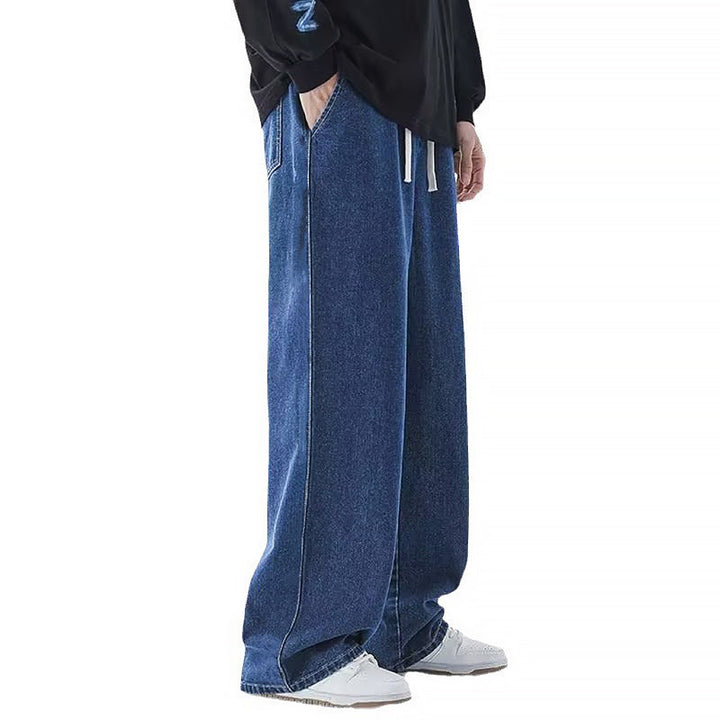 Man bär svarta herrjeans med vida ben och avslappnad passform. Trendiga och bekväma sommarjeans för herrmode.