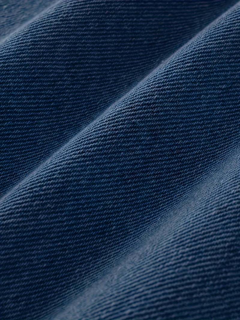 Textur på stretchig denim av trasiga herrjeans, visar kvalitet och design