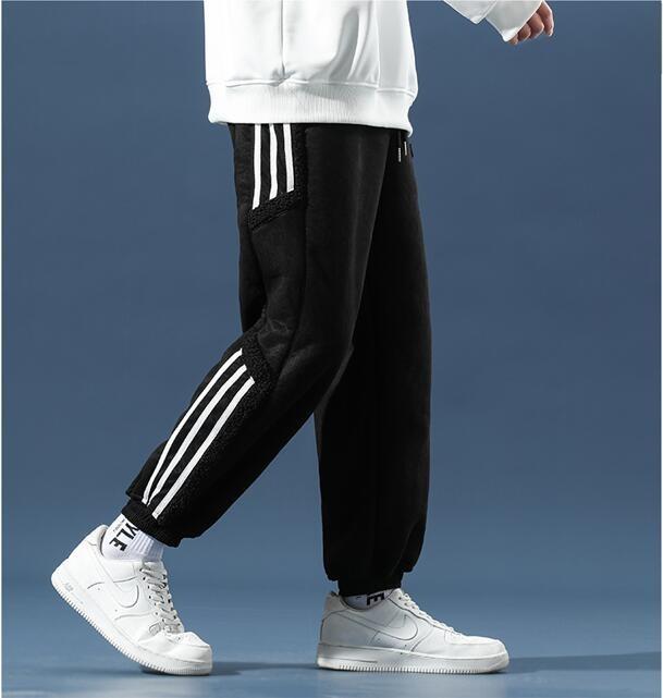 Detaljbild på herrjoggers sidosträckning. Trendiga byxor i svart, utmärkta för sportig streetwear.