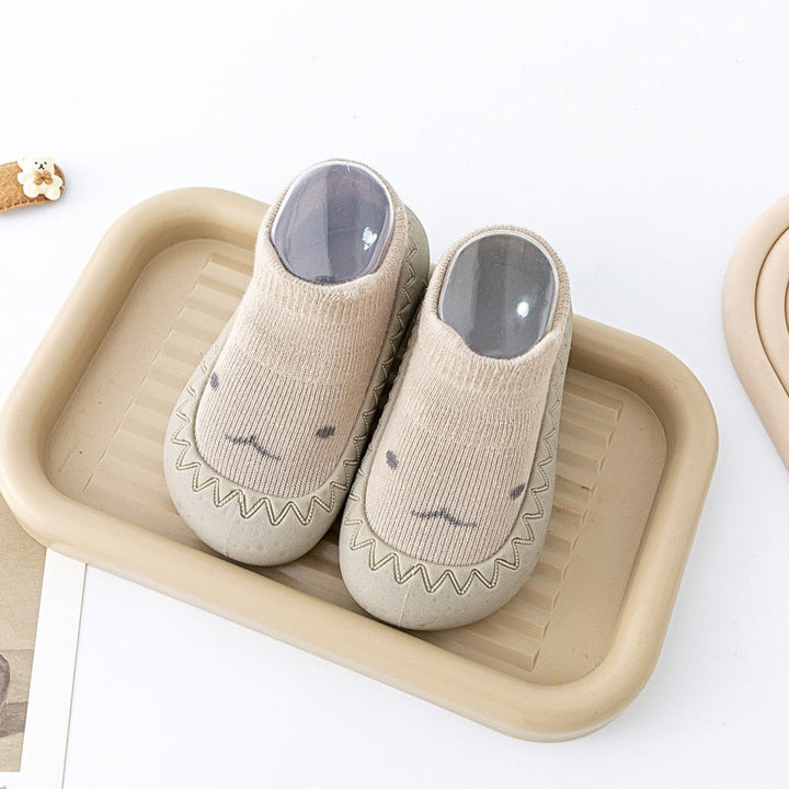 Khakifärgade mjuka babygummiskor med tecknat motiv, perfekta som förstastegsskor.