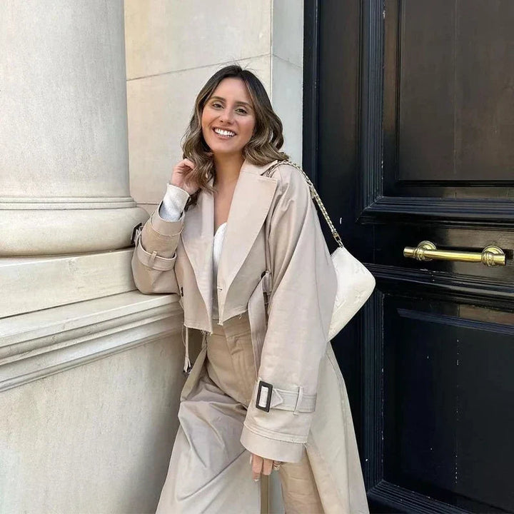 Dammodell bär elegant beige trenchcoat, klassiskt ytterplagg för en tidlös look. Vår- och höstjacka.