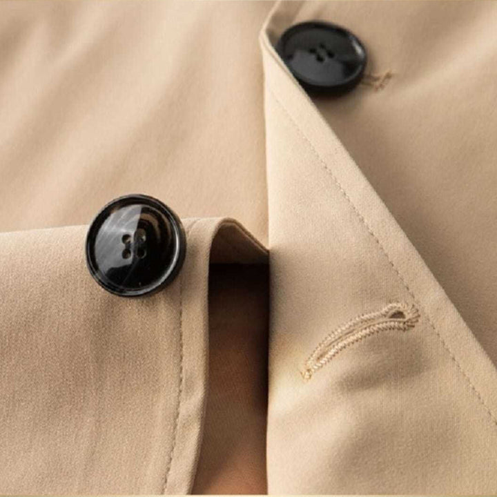 Beige kort damtrenchcoat, ett klassiskt ytterplagg som skyddar mot väder. Elegant och funktionell.
