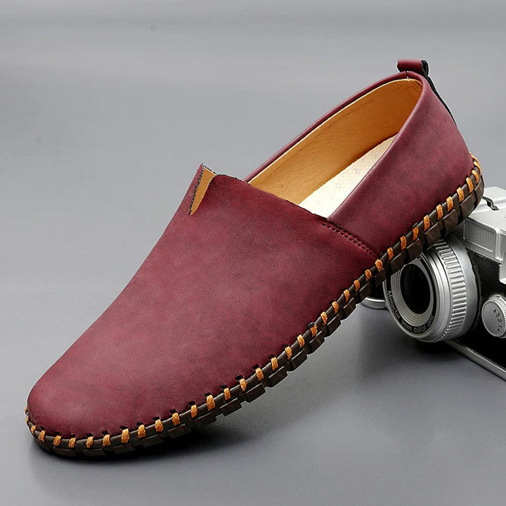 Sidovy av eleganta herrloafers i läder, klassisk slip-on design. Idealisk för smart casual.