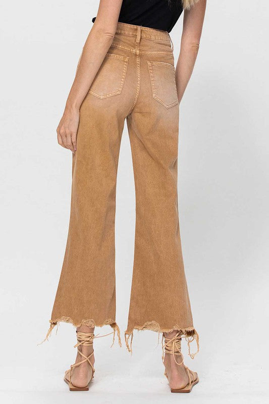 Stack av hopfällda crop flare jeans för kvinnor, vintage 90-talsstil, denimfärg på enkel bakgrund.