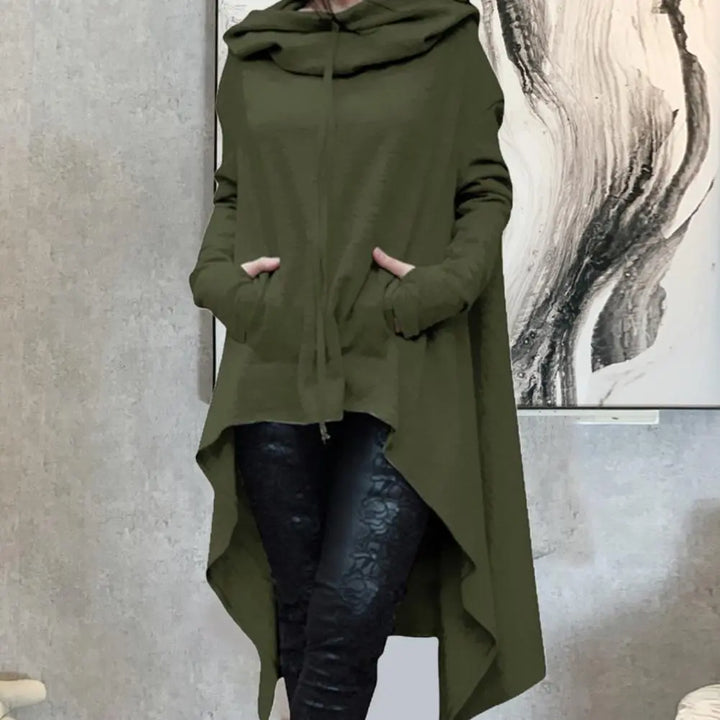 Modell bär asymmetrisk kvinnors huvtröja. Trendig pullover med fisksvansfåll som ger modern vardagsstil.
