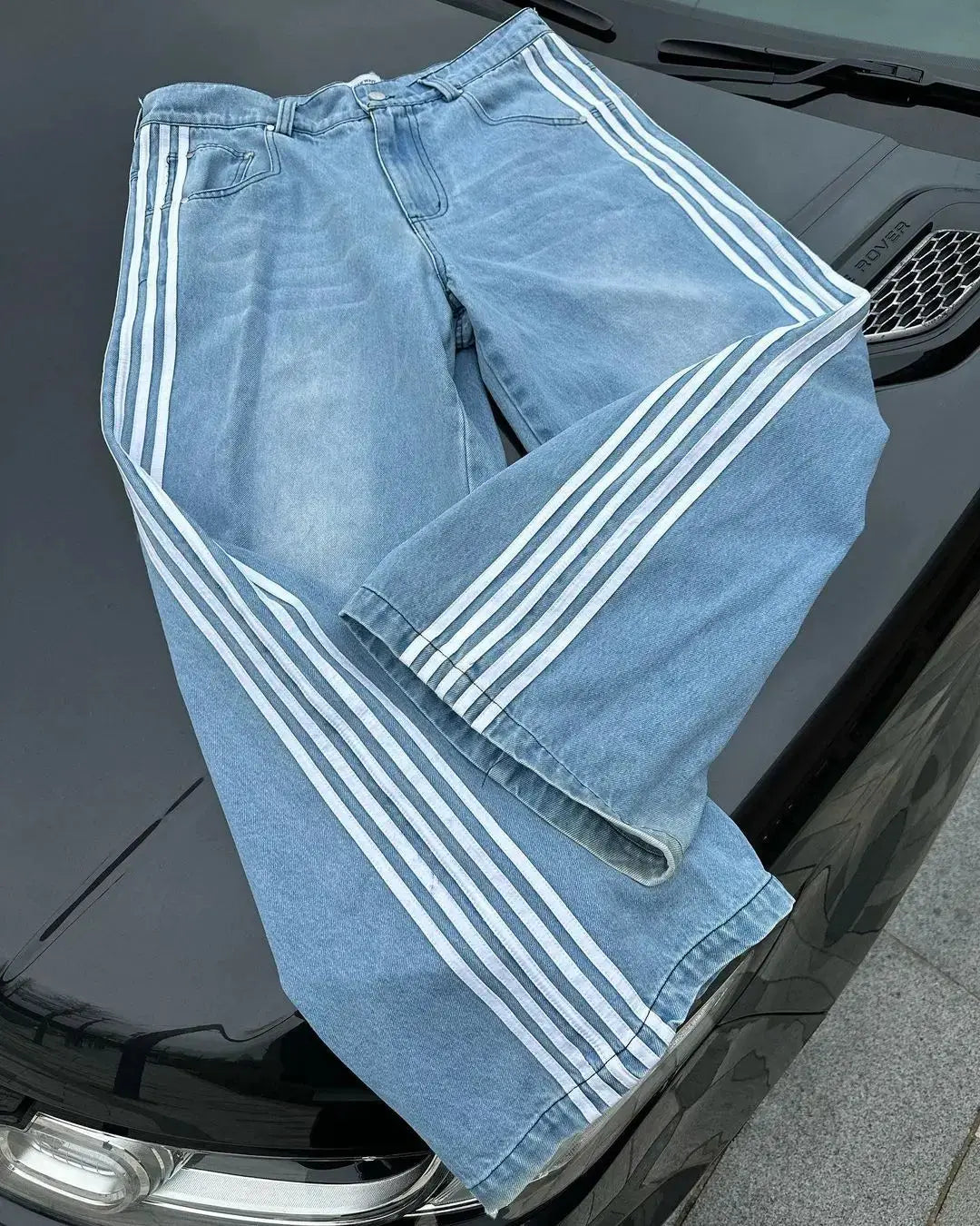 Detaljbild av Y2K baggy jeans: hög midja, avslappnad passform och sidränder i blått tyg