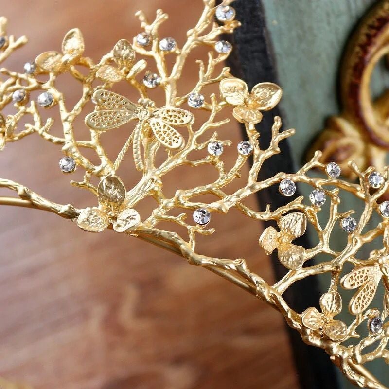 Närbild på guld libell tiara, en elegant håraccessoar för bröllop eller fest, med strasskrona