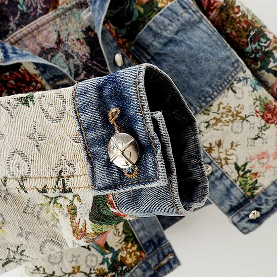 Ryggvy av kvinnors jeansjacka med detaljerat handmålat blommönster. Chic sommar- och vårjacka.