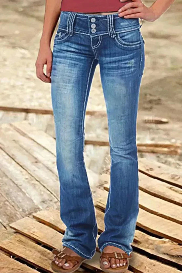 Modell bär trendiga högmidjade bootcut jeans med slitna detaljer och bekväm passform